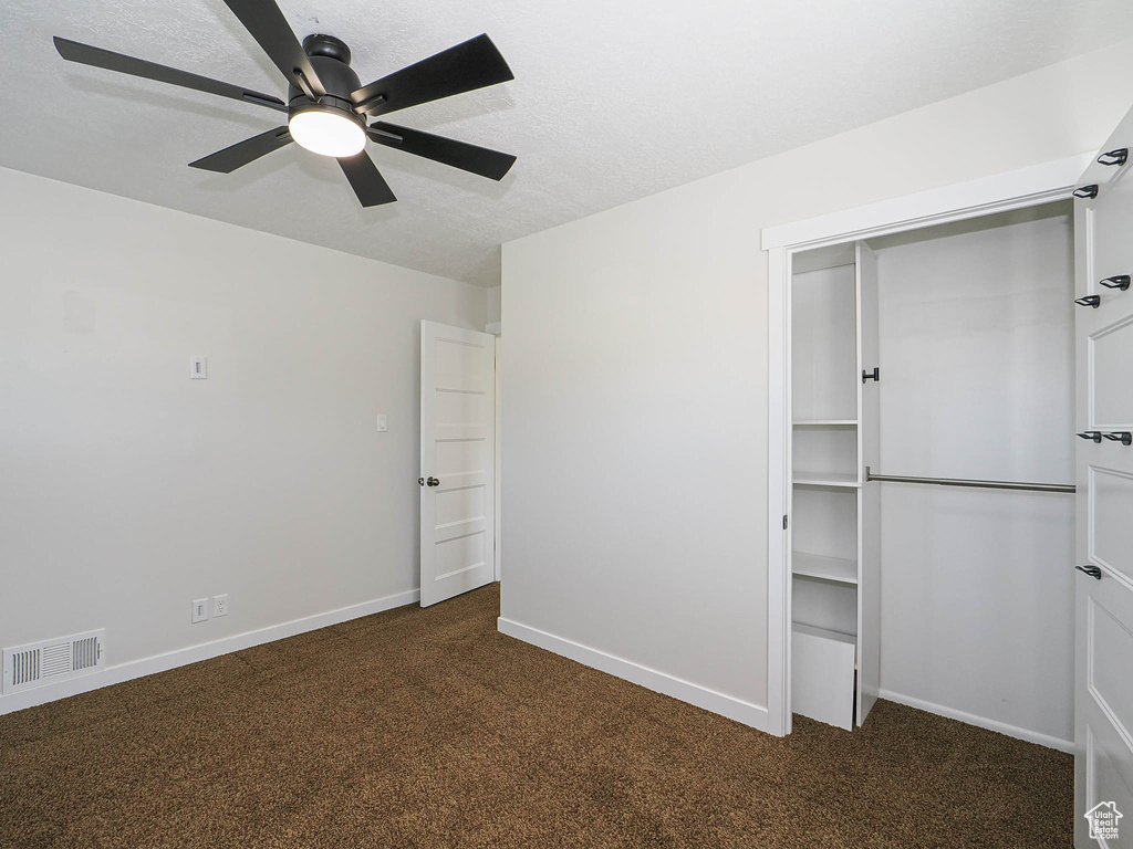 Unfurnished bedroom with carpet floors, a closet, ceiling fan, and a textured ceiling