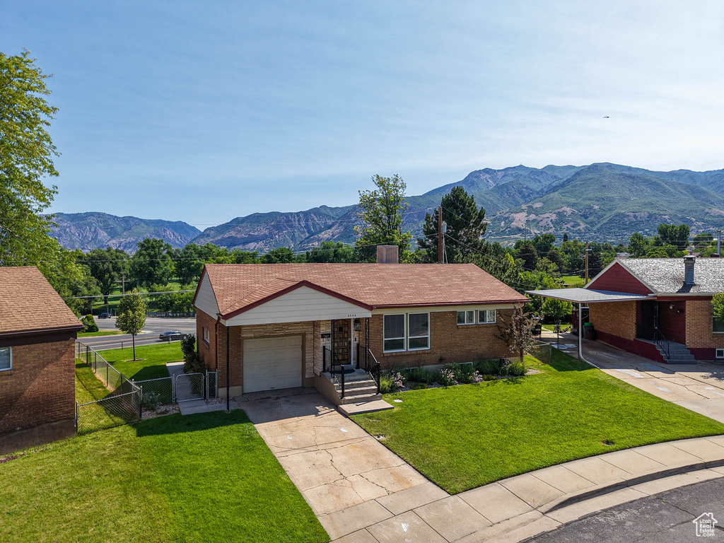Ranch-style home with a garage, driveway, brick siding, and a mountain view
