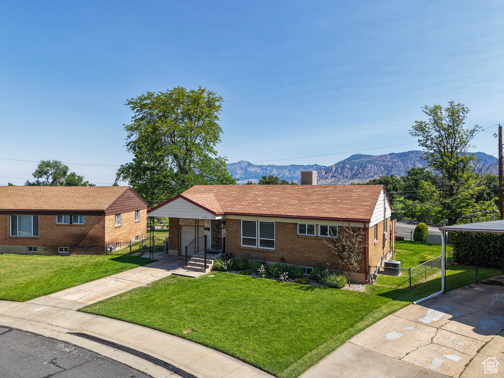 View of front facade with concrete driveway, a mountain view, brick siding, a garage, and a gate