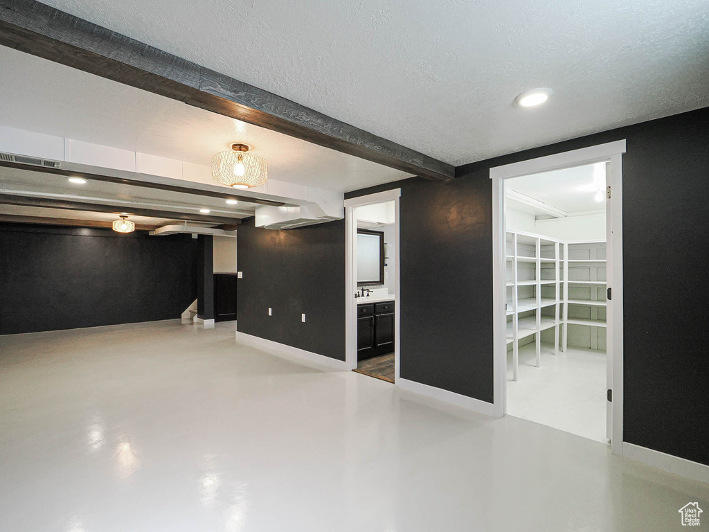 Empty room featuring finished concrete floors, beamed ceiling, and recessed lighting