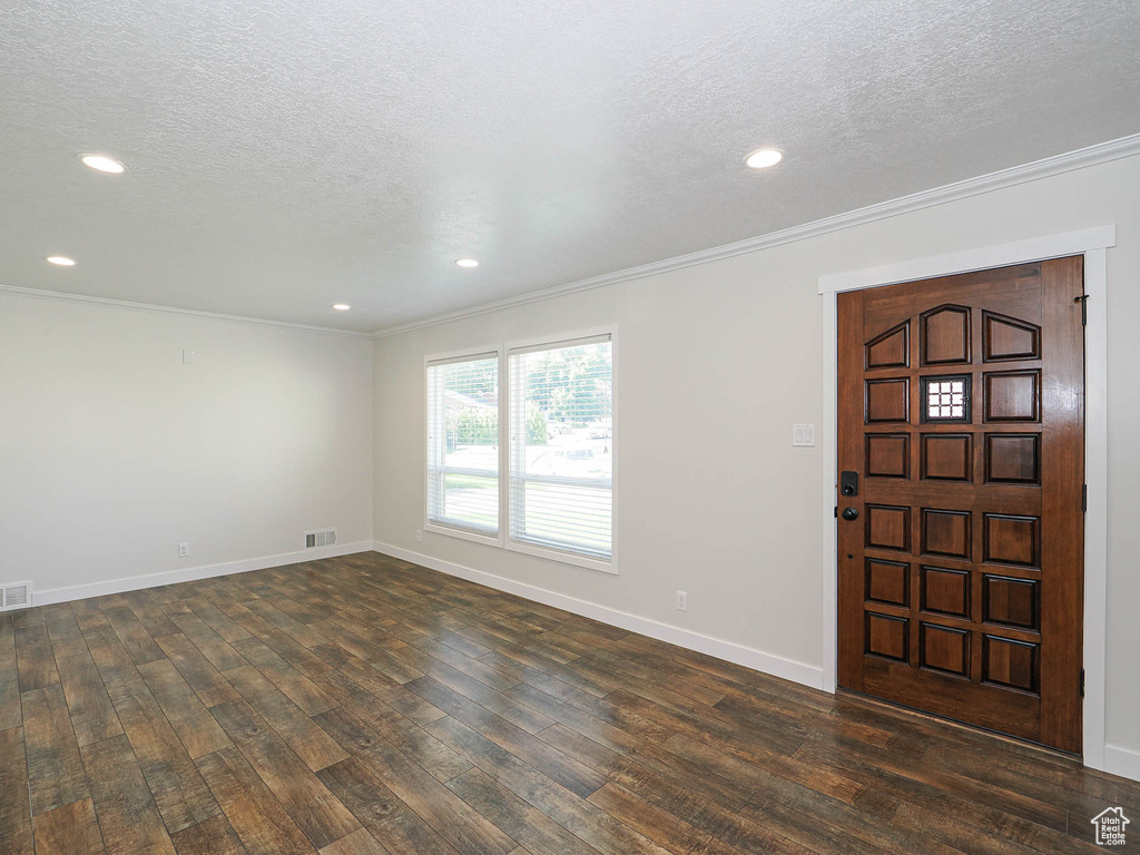 Entrance foyer with ornamental molding, dark wood-style floors, a textured ceiling, and recessed lighting