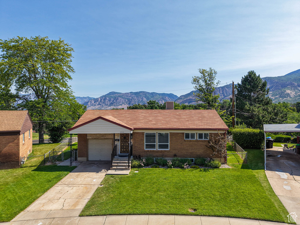 View of front of home featuring concrete driveway, a mountain view, brick siding, and a chimney