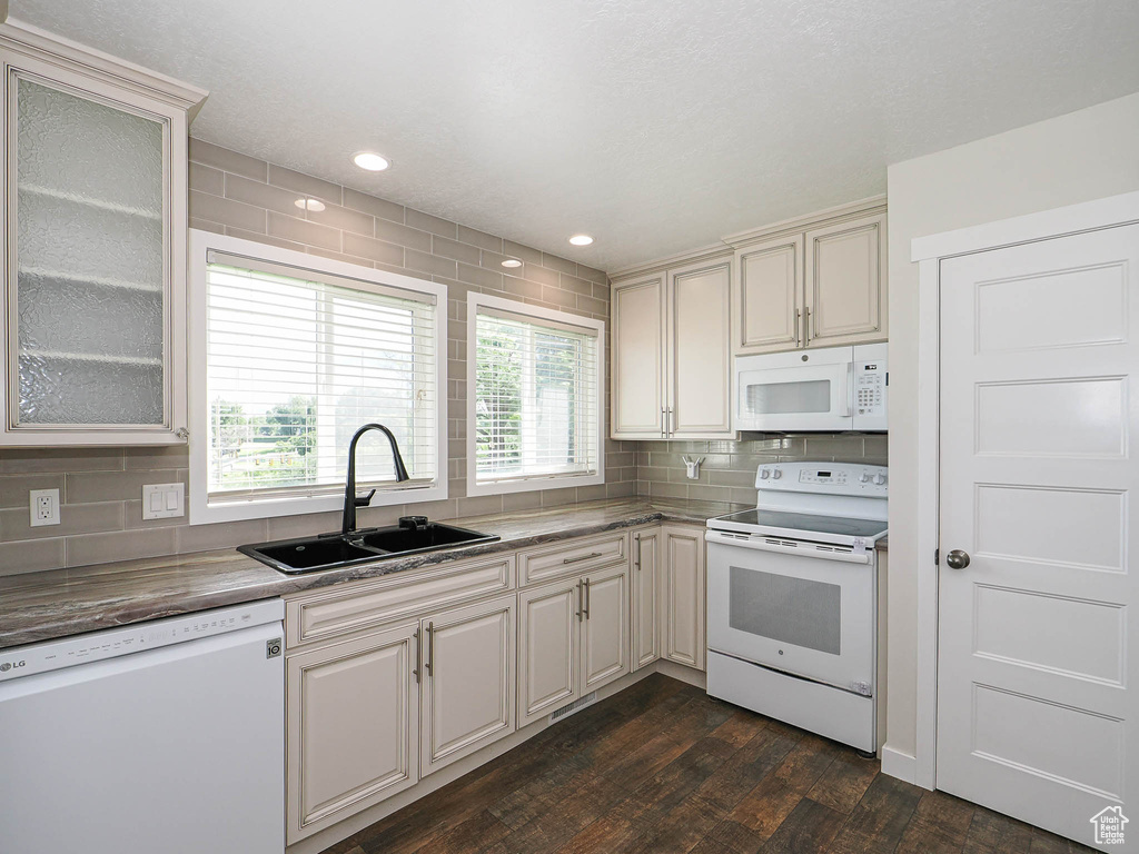 Kitchen featuring white appliances, dark wood-type flooring, backsplash, glass insert cabinets, and recessed lighting