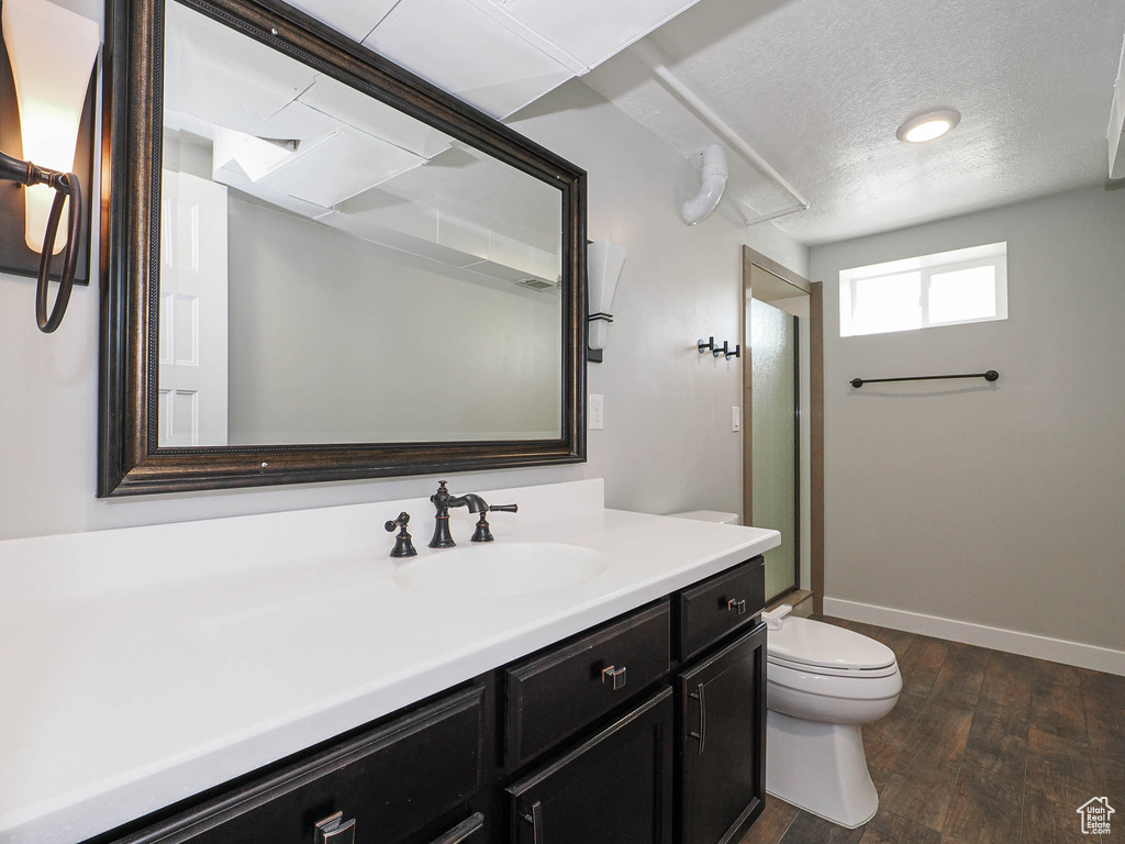Bathroom with vanity, wood finished floors, a textured ceiling, and a shower