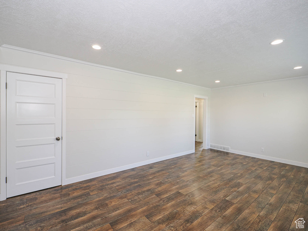 Unfurnished room with dark wood-type flooring, ornamental molding, a textured ceiling, and recessed lighting