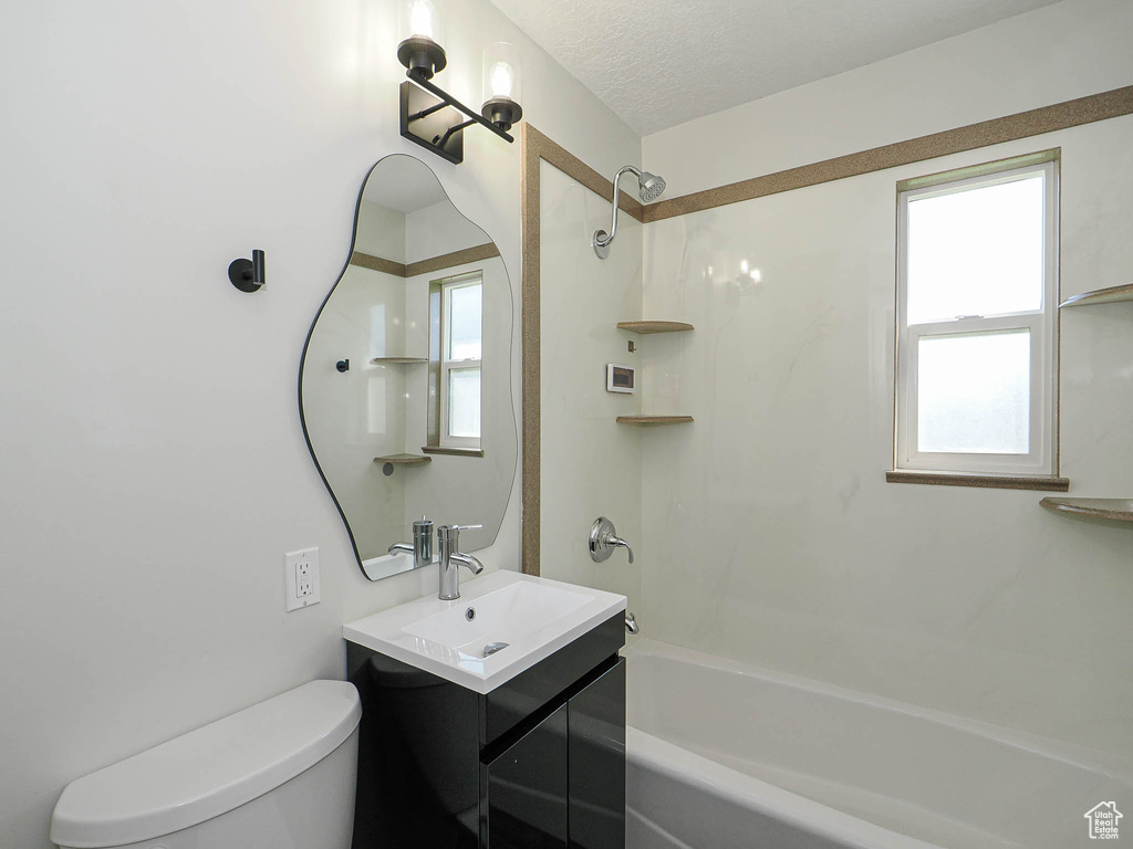 Bathroom featuring  shower combination, vanity, plenty of natural light, and a textured ceiling