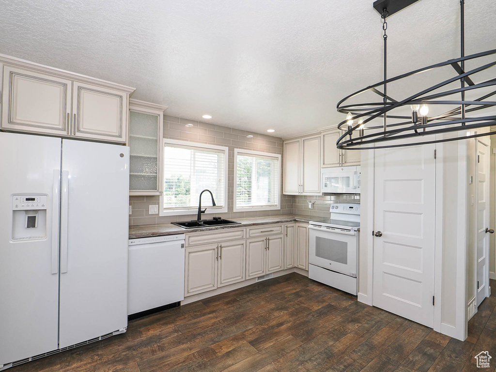 Kitchen featuring white appliances, dark wood-type flooring, decorative backsplash, a chandelier, and glass insert cabinets