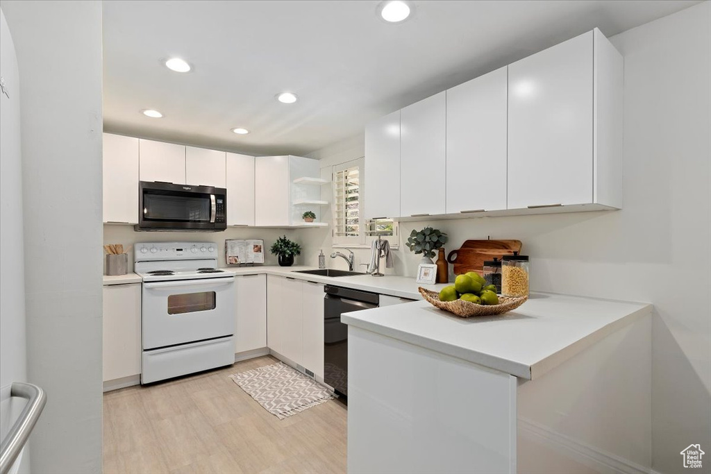 Kitchen with stainless steel microwave, white electric range oven, dishwashing machine, light wood-style floors, and open shelves