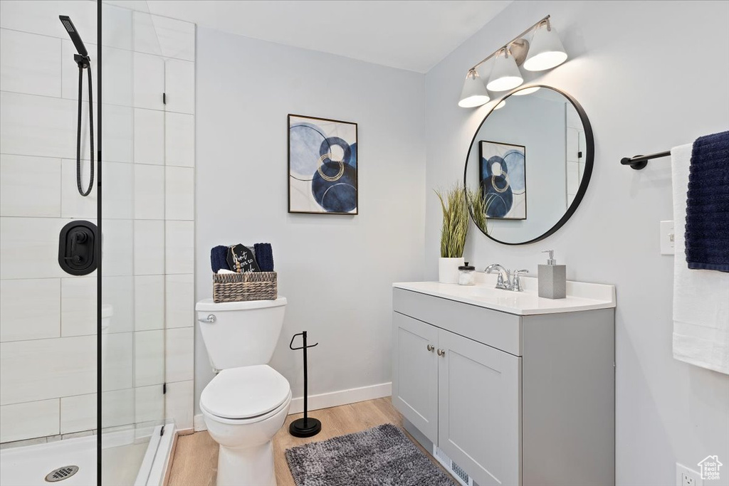 Bathroom featuring vanity, tiled shower, and wood finished floors