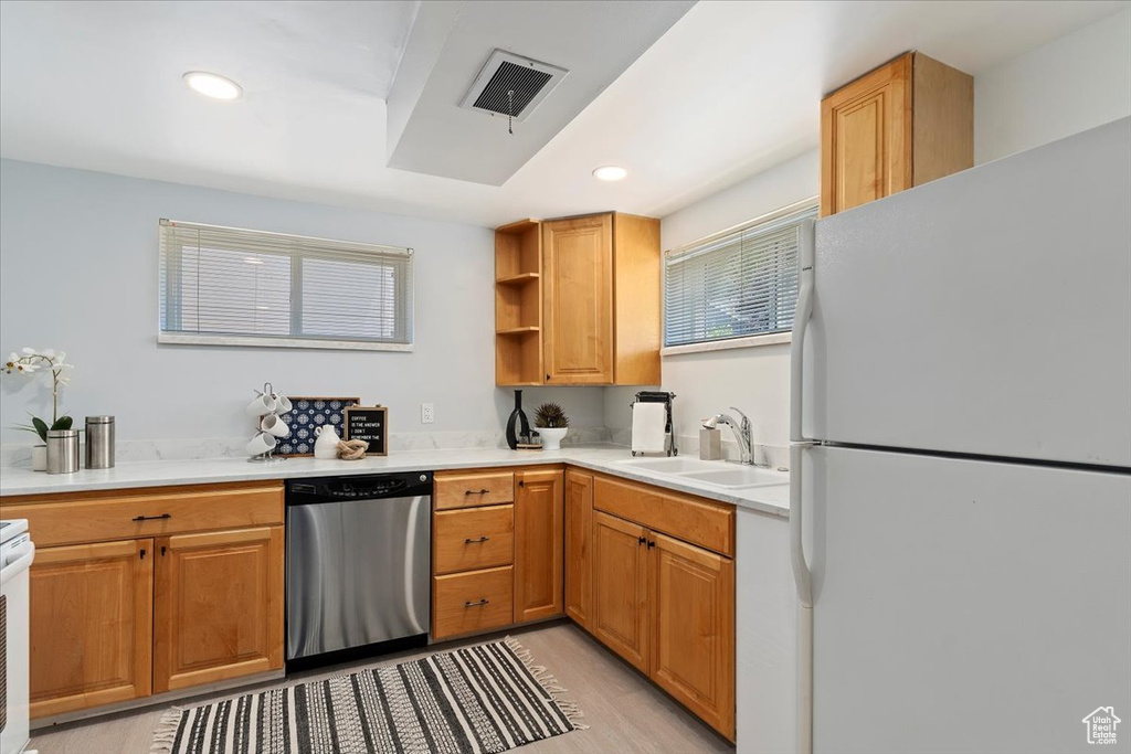Kitchen with freestanding refrigerator, dishwasher, light countertops, light wood-style flooring, and recessed lighting