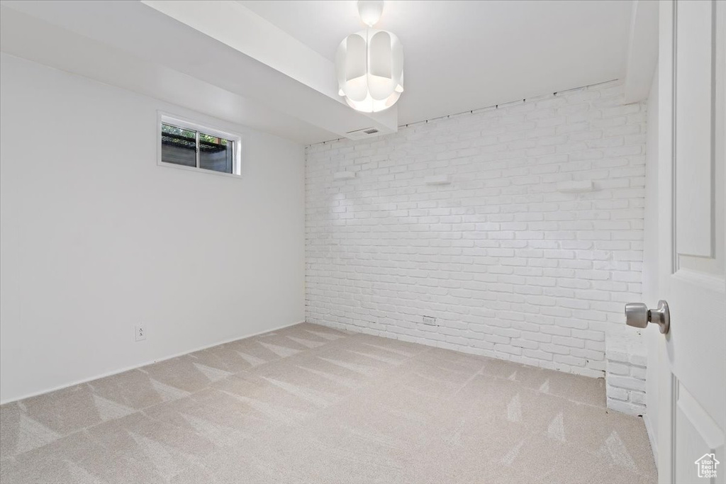 Carpeted empty room featuring brick wall
