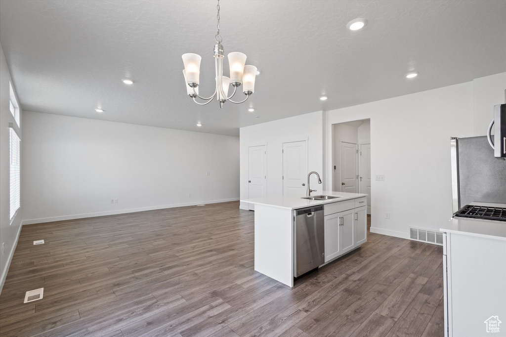 Kitchen with stainless steel appliances, wood finished floors, recessed lighting, a kitchen island with sink, and light countertops