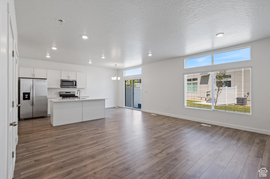 Kitchen with appliances with stainless steel finishes, recessed lighting, open floor plan, dark wood-style flooring, and white cabinetry