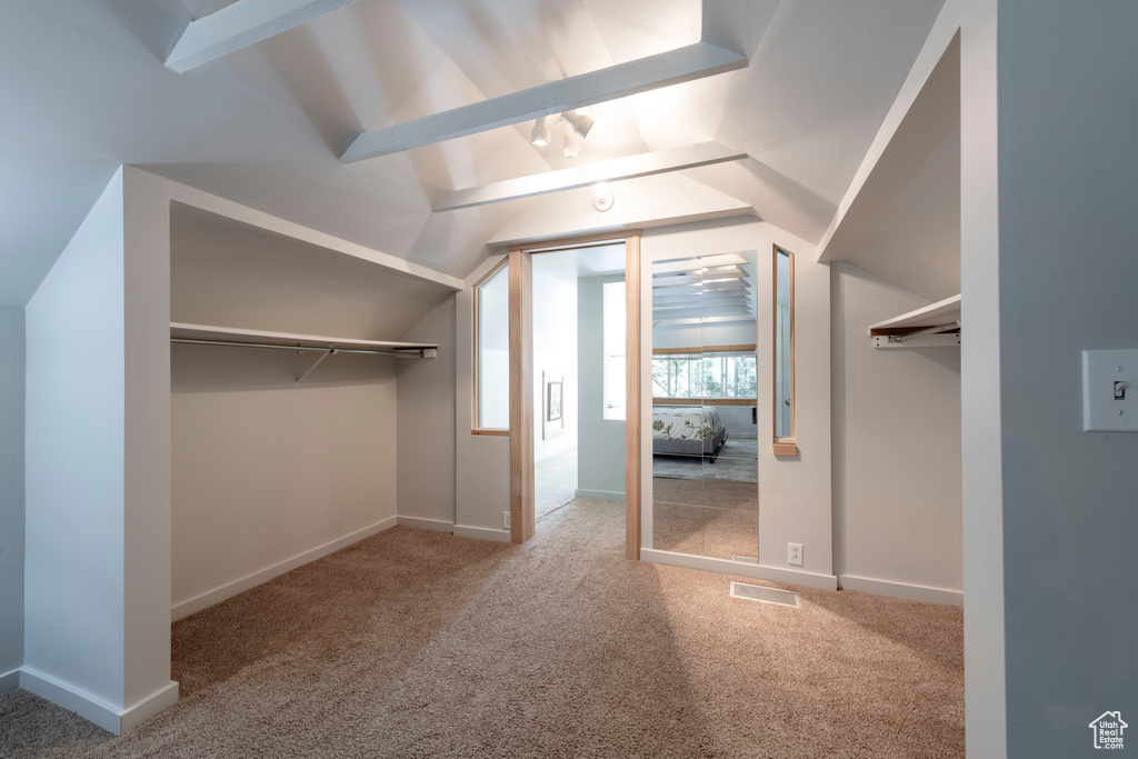 Walk in closet with carpet floors and lofted ceiling