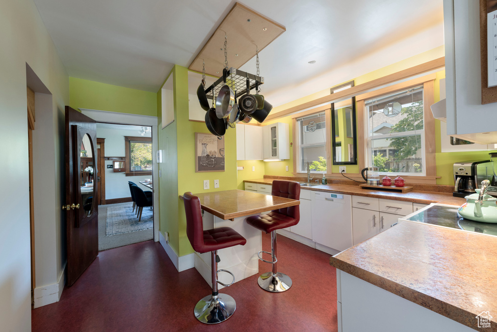 Kitchen with dishwasher, white cabinets, glass insert cabinets, and a breakfast bar