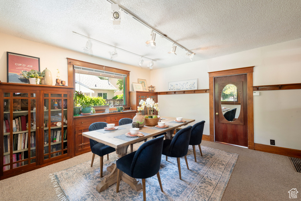 Carpeted dining area featuring a textured ceiling and baseboards