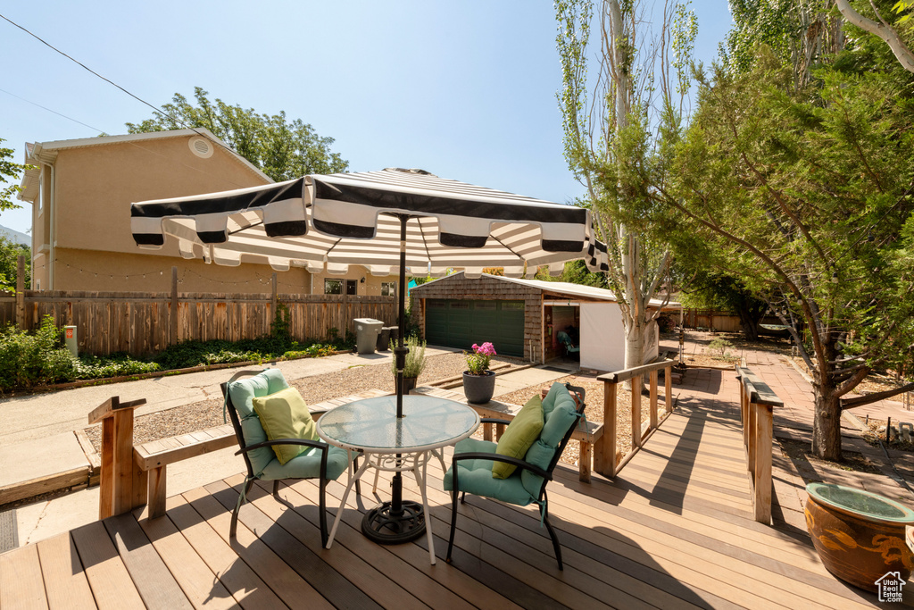 Wooden terrace with an outbuilding, a fenced backyard, and outdoor dining space