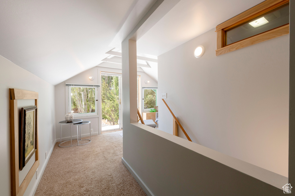 Hall featuring an upstairs landing, vaulted ceiling, and carpet floors
