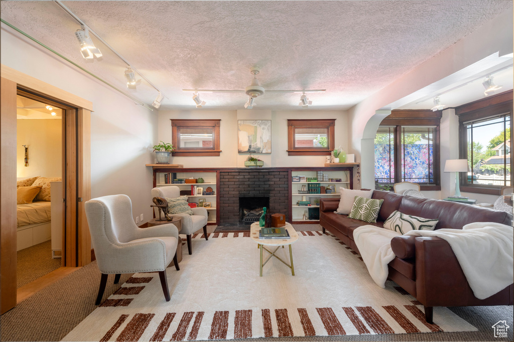 Living area featuring track lighting, a fireplace, and a textured ceiling