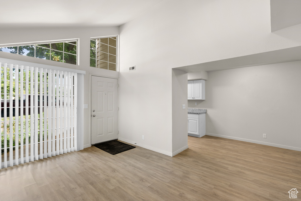 Entryway with light wood-type flooring and a towering ceiling