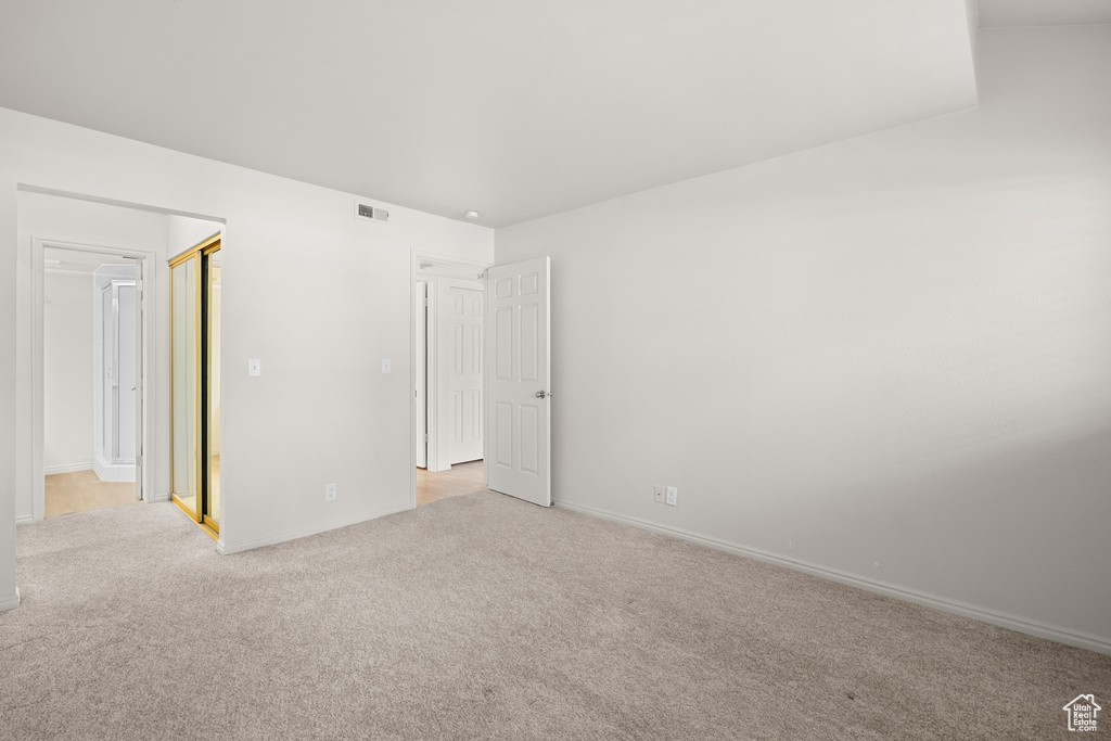 Unfurnished bedroom with light carpet and baseboards