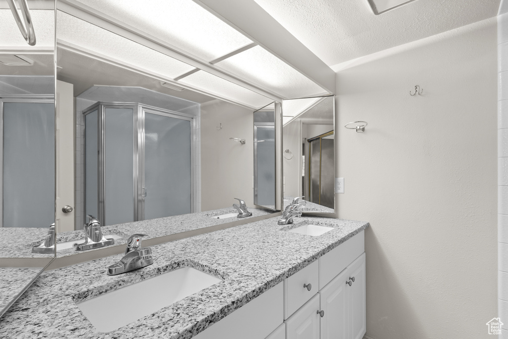 Full bathroom featuring double vanity and a stall shower
