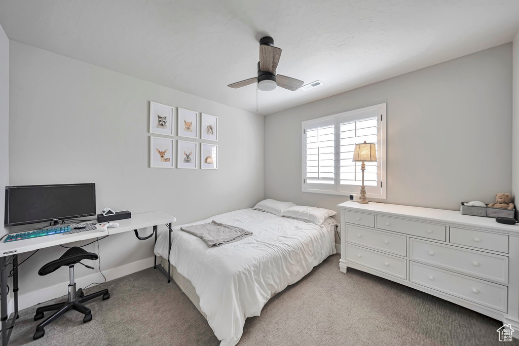 Carpeted bedroom featuring ceiling fan and a desk
