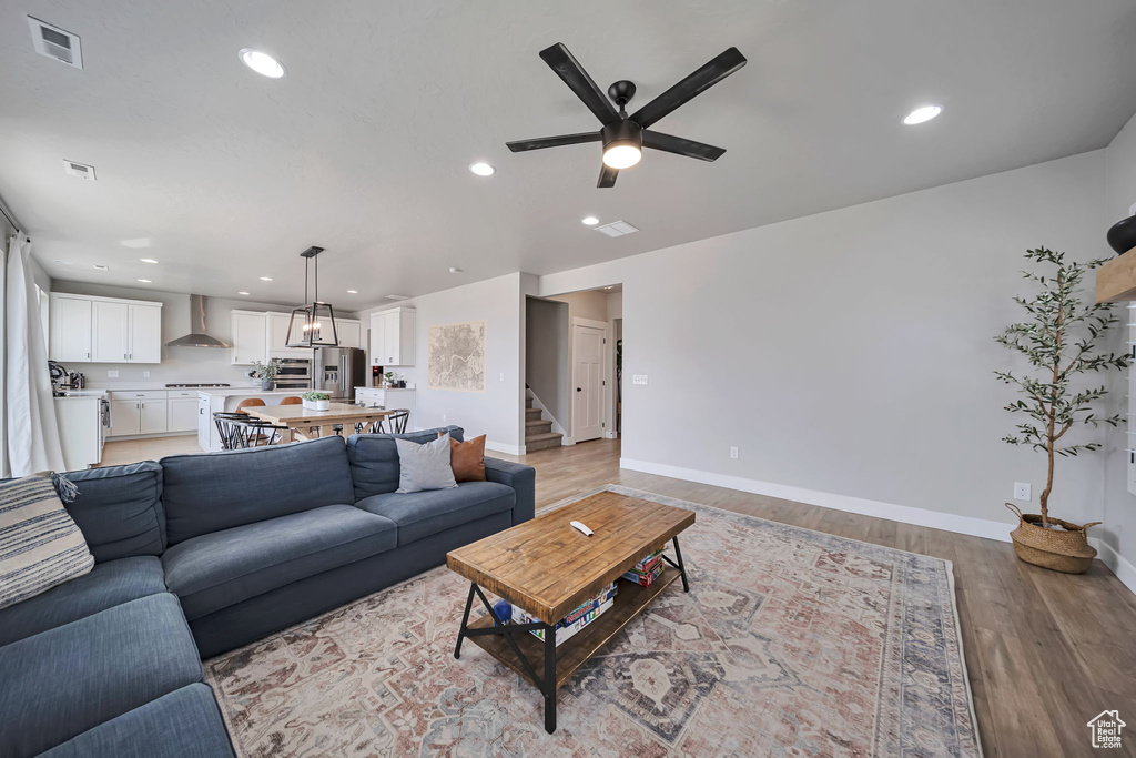Living area with a ceiling fan, light wood-style flooring, stairs, and recessed lighting