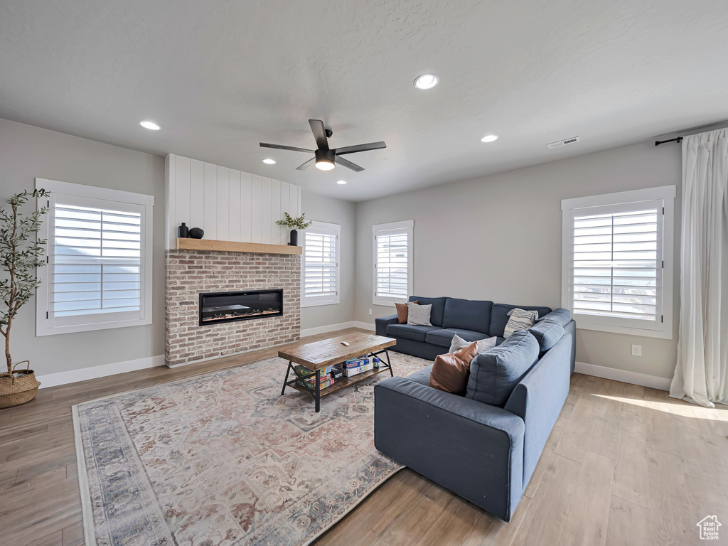Living room featuring ceiling fan, light wood-type flooring, recessed lighting, and a fireplace