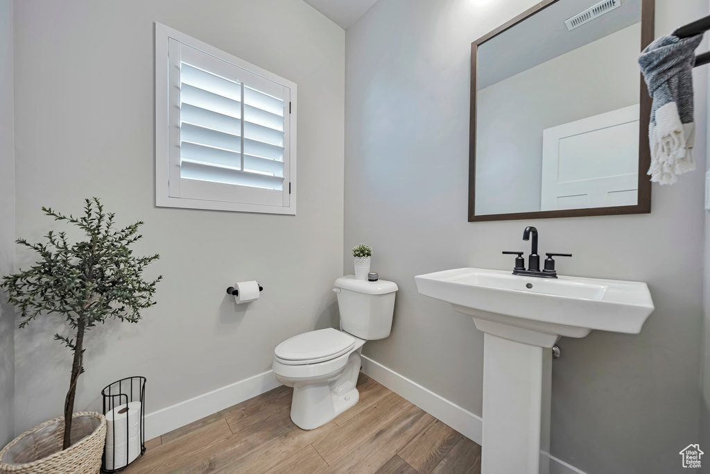 Half bath with wood finished floors and baseboards
