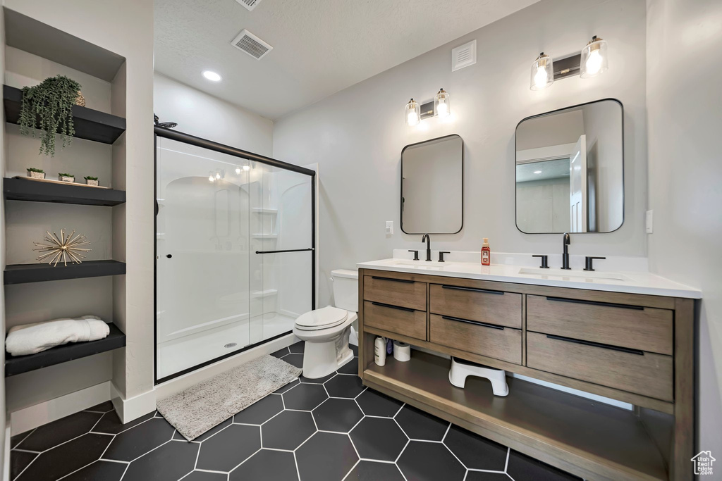 Full bathroom with double vanity, a stall shower, and tile patterned flooring