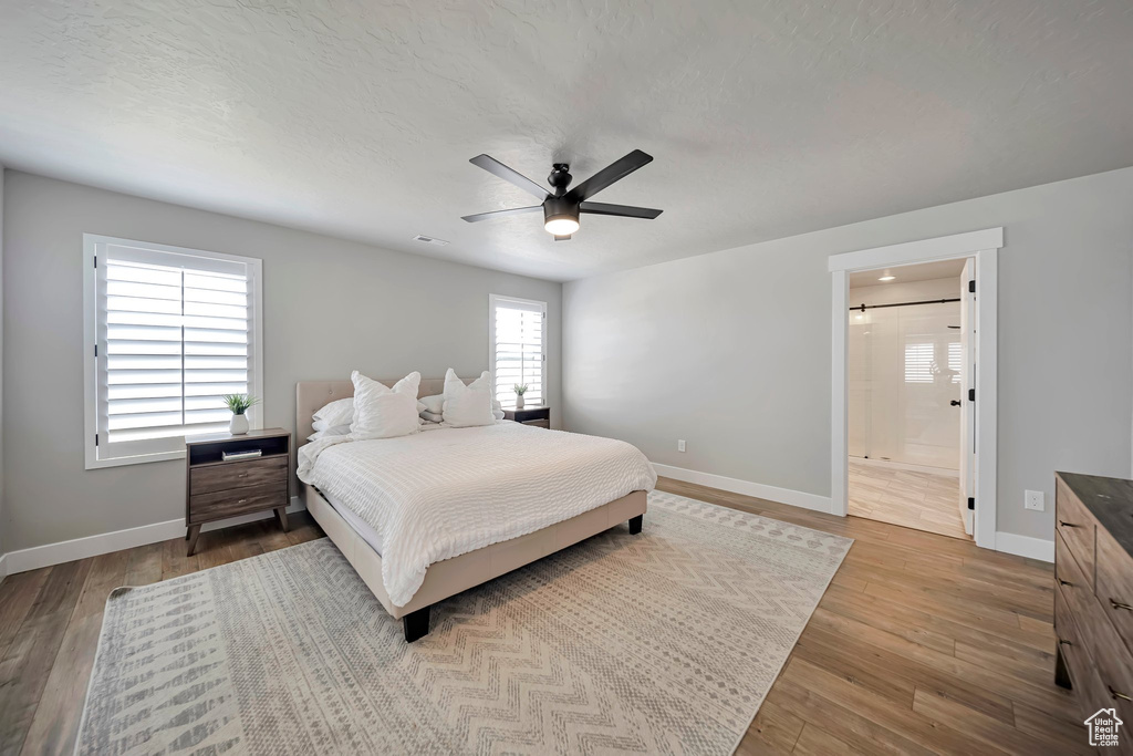 Bedroom featuring wood finished floors, ensuite bathroom, and a ceiling fan