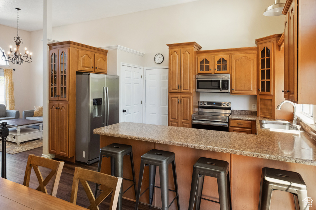 Kitchen with stainless steel appliances, a sink, a peninsula, a chandelier, and glass insert cabinets