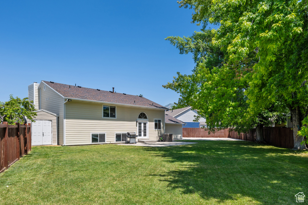 Rear view of property with a fenced backyard, a patio area, and french doors