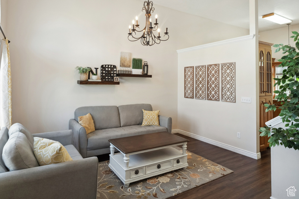 Living area featuring wood finished floors, a chandelier, baseboards, and lofted ceiling