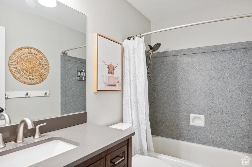 Bathroom featuring toilet, shower / bath combo with shower curtain, and vanity