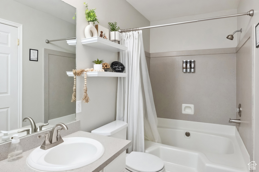 Bathroom with toilet, shower / tub combo with curtain, and vanity