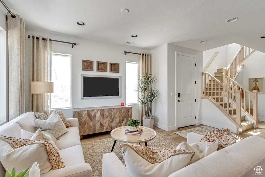 Living area featuring plenty of natural light, wood finished floors, stairs, and recessed lighting