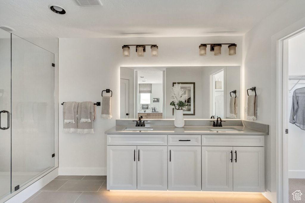 Full bathroom with double vanity, a stall shower, and tile patterned flooring