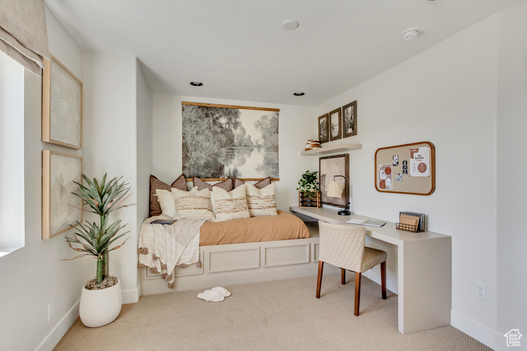 Carpeted bedroom with a desk and baseboards