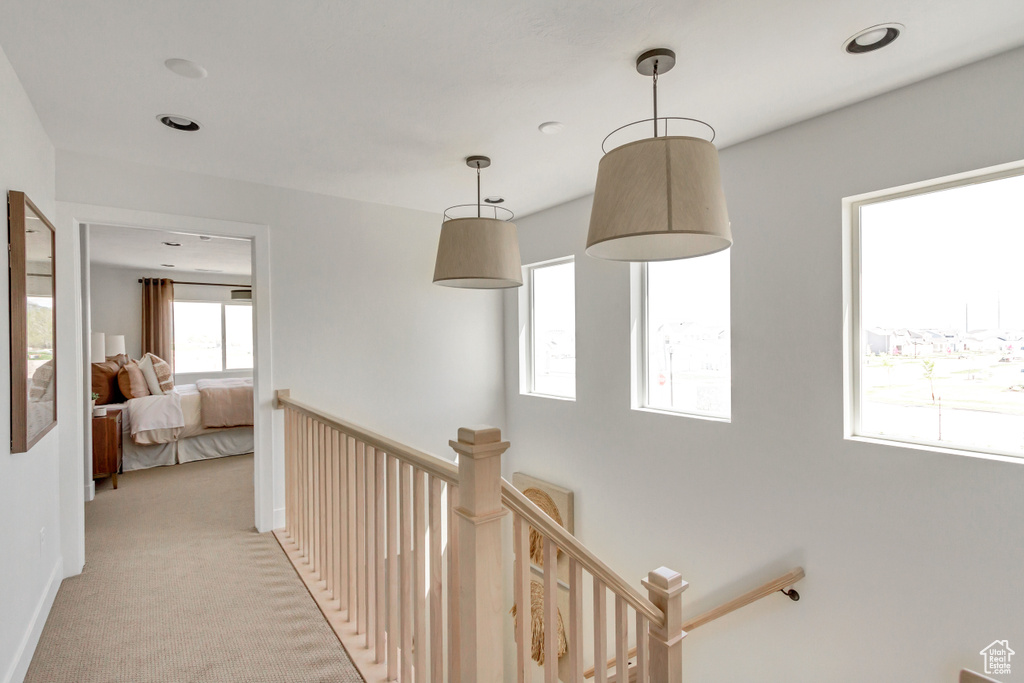 Hallway with an upstairs landing and light colored carpet