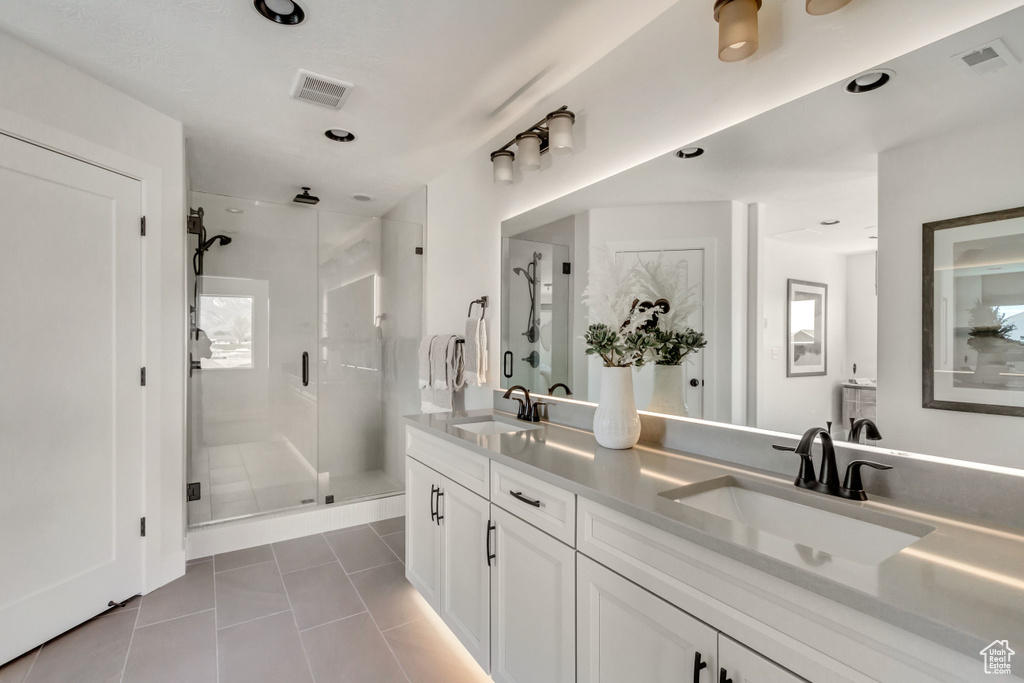Bathroom featuring tile patterned flooring, a shower stall, double vanity, and recessed lighting