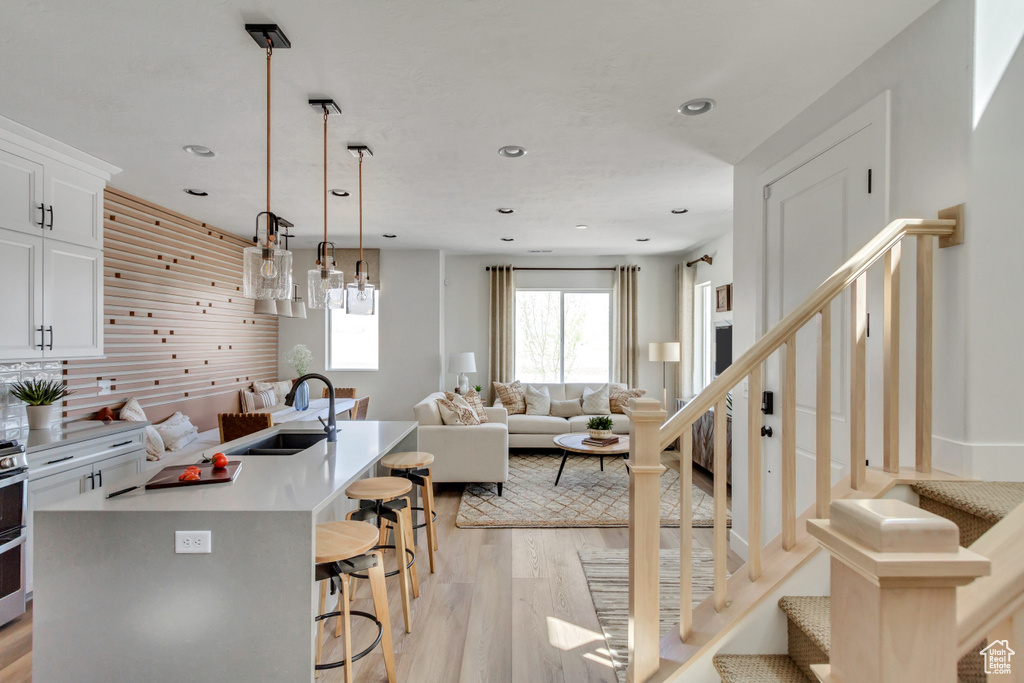 Kitchen featuring a kitchen breakfast bar, light wood-style flooring, open floor plan, recessed lighting, and an island with sink
