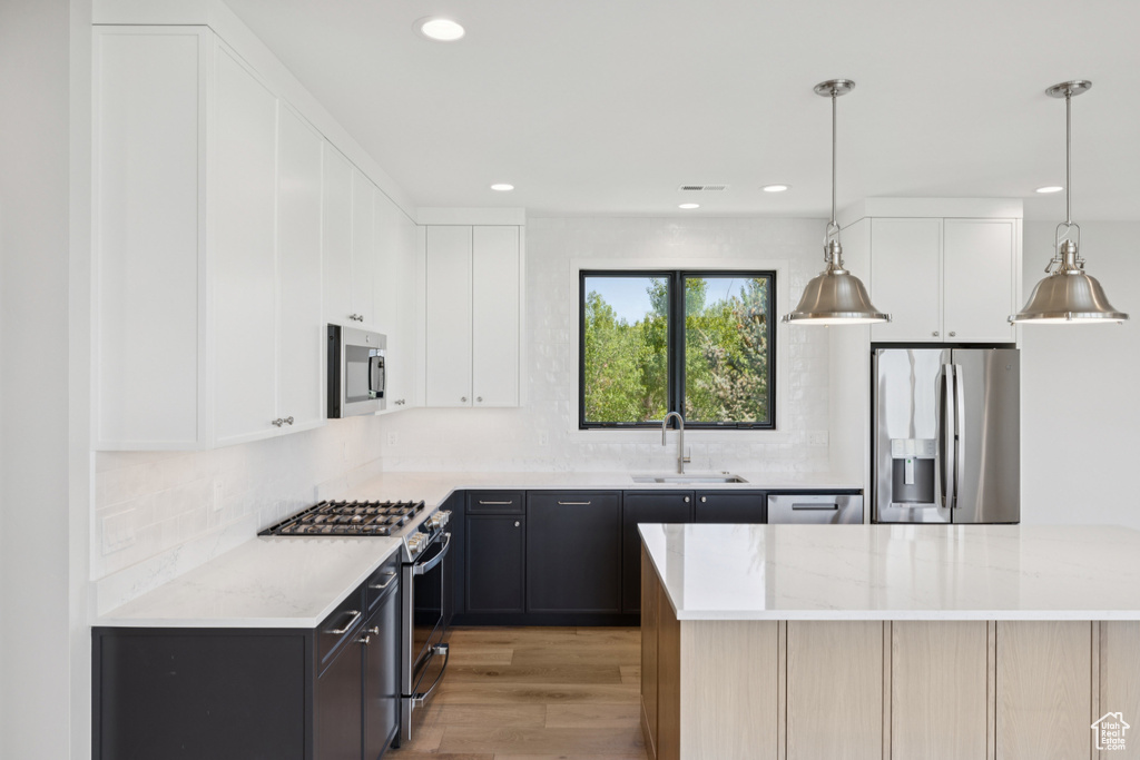Kitchen featuring appliances with stainless steel finishes, light wood finished floors, decorative backsplash, recessed lighting, and white cabinetry