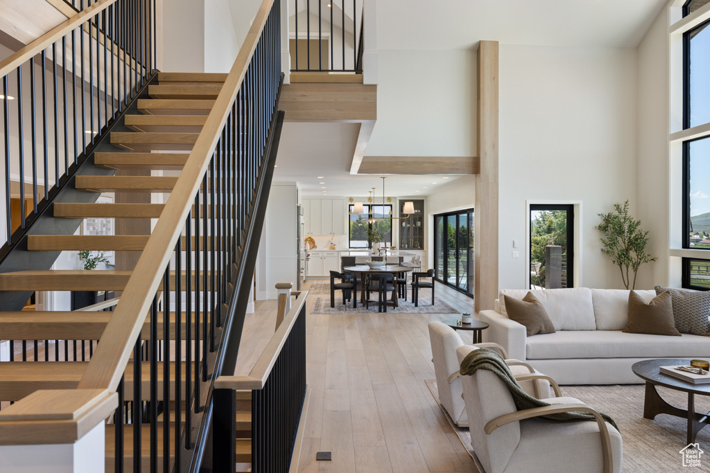 Living area featuring a towering ceiling, wood-type flooring, and stairs