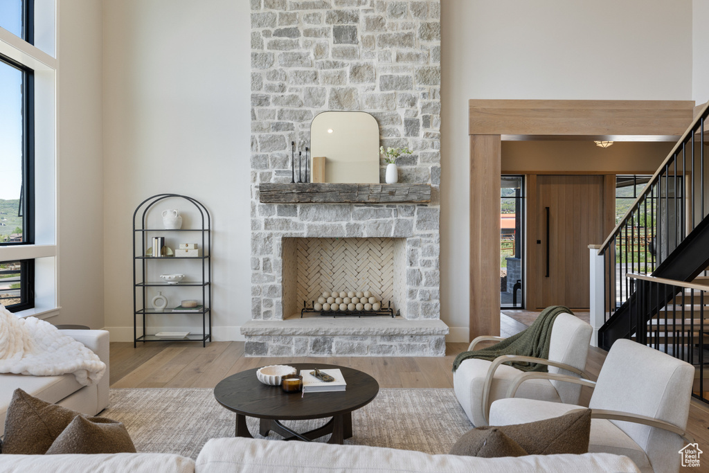 Living room with wood finished floors, stairs, a fireplace, and plenty of natural light