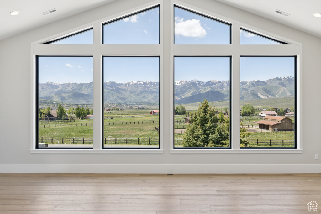 Empty room featuring plenty of natural light, wood finished floors, a mountain view, lofted ceiling, and recessed lighting