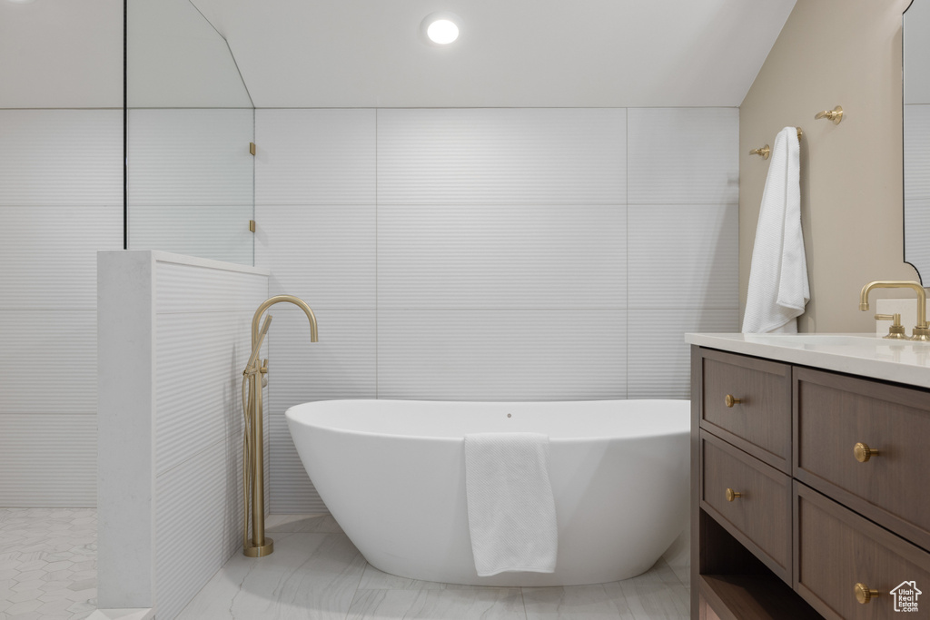 Bathroom featuring vanity, a soaking tub, and walk in shower