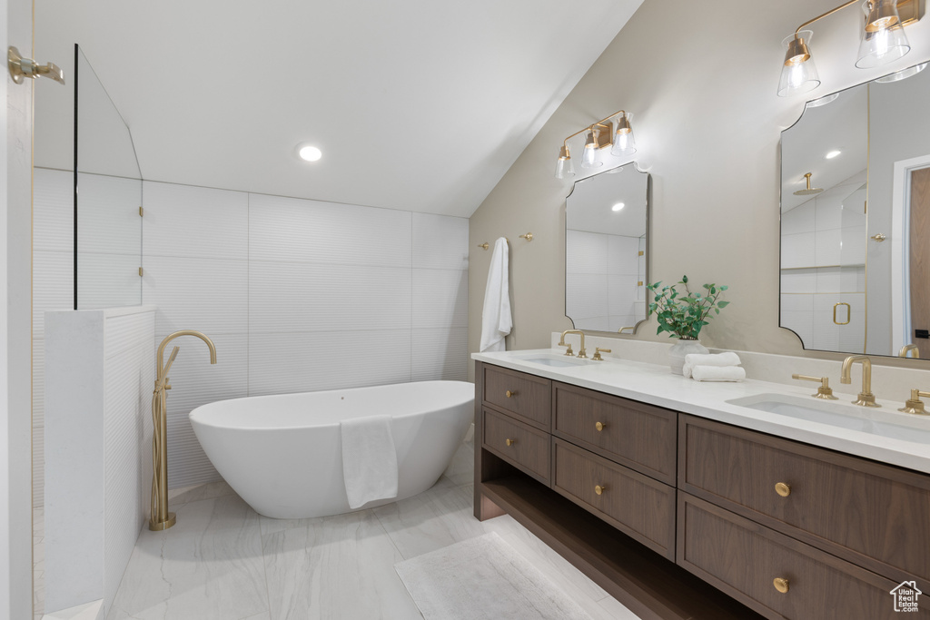 Full bath with double vanity, a soaking tub, a shower, marble finish floors, and tile walls