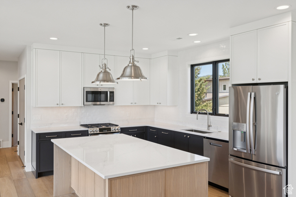Kitchen featuring stainless steel appliances, a center island, light wood-type flooring, backsplash, and recessed lighting
